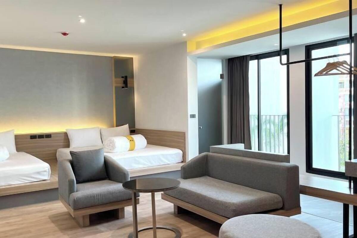 Une chambre d’hôtel moderne, équipée d’un lit, de deux canapés, d’une petite table et d’une grande fenêtre donnant sur un paysage agréable.