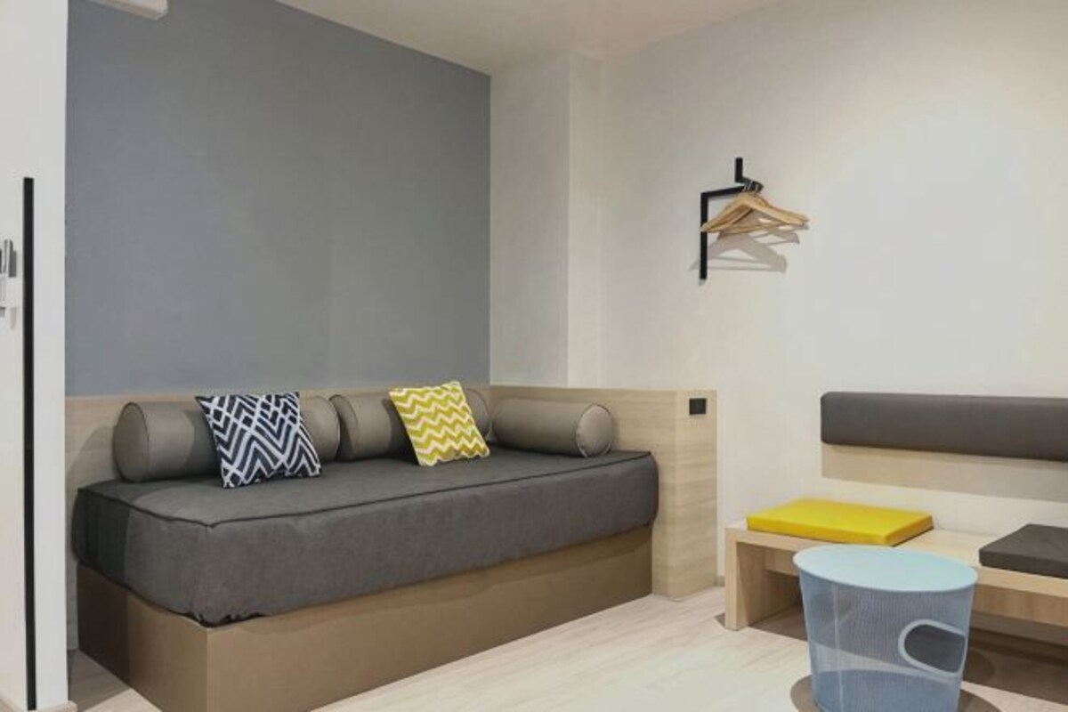 A modern living room with a sofa, a small table, a hanging light fixture, and a wall-mounted coat rack.