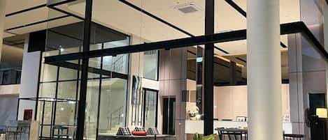 Un edificio moderno con amplios ventanales, una zona de estar con sofás y sillones, y una escalera que conduce a un nivel superior.
