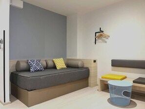 Una habitación moderna con sofá, una mesita, una lámpara colgante y un cubo de basura.