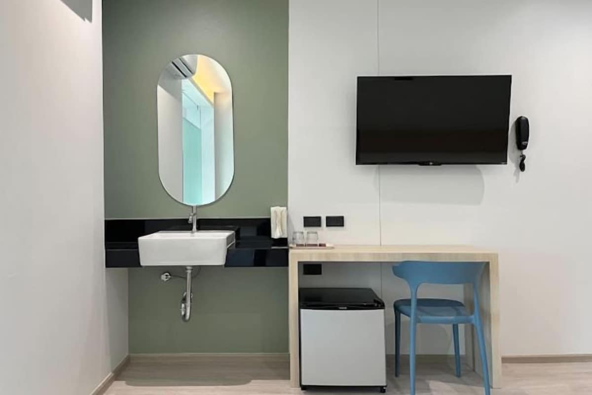 Un baño moderno con lavamanos, espejo y televisor de pantalla plana montado en la pared.