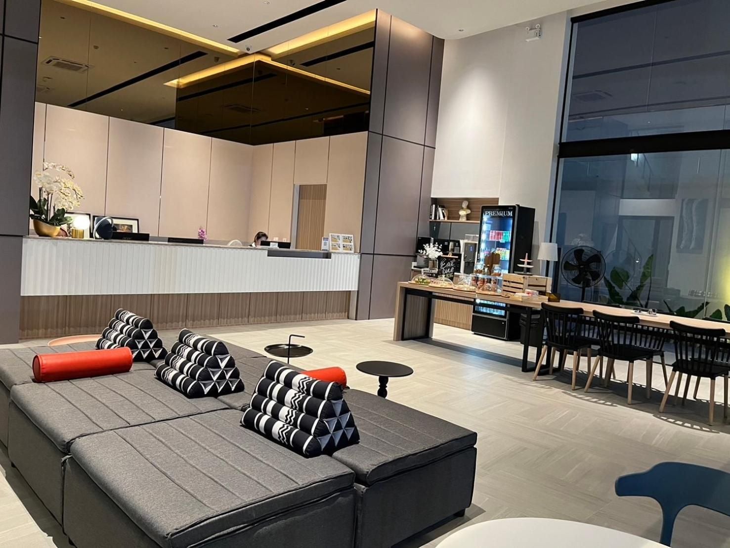 Un moderno vestíbulo de hotel con recepción, zona de estar y un bar.