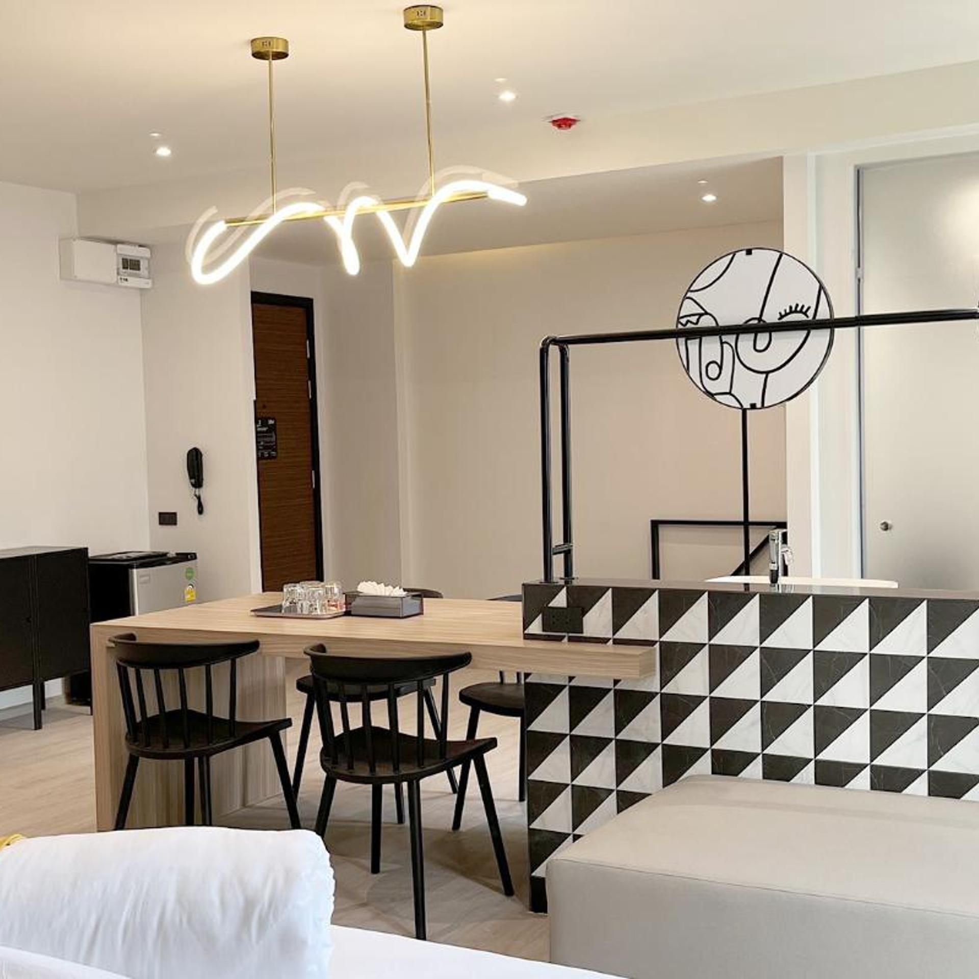 Ein moderner Essbereich mit Holztisch, schwarzen Stühlen und einer Sitzbank mit geometrischem Muster.