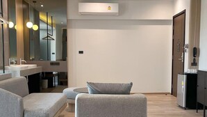 Una habitación de hotel moderna con sofá, una mesita, un espejo y minibar.