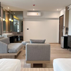 Una habitación de hotel moderna con sofá, una mesita, un espejo y minibar.