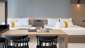 Una habitación de hotel moderna con una cama grande, dos mesitas de noche, un escritorio con sillas y una lámpara de techo original.