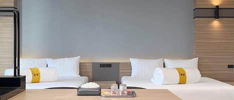 A modern hotel room with a large bed, two bedside tables, a desk with chairs, and a unique ceiling light fixture.