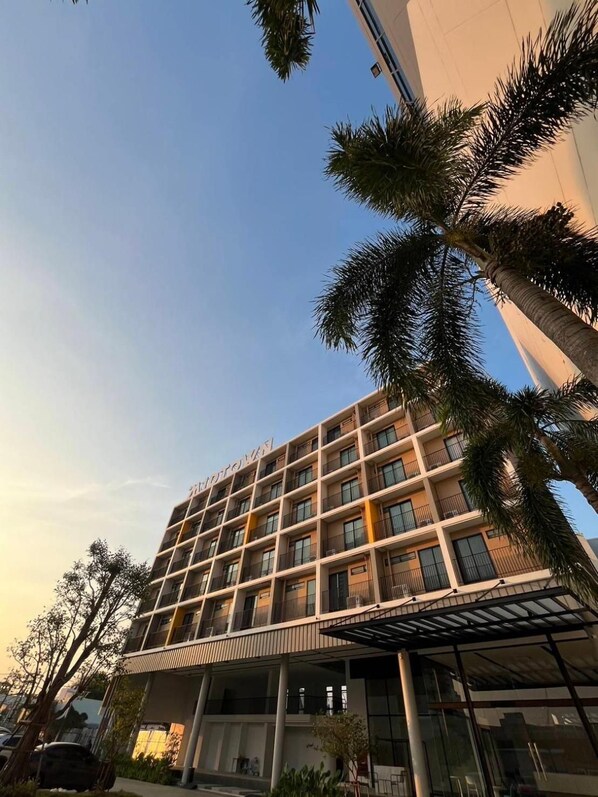 Un hotel de varios pisos con un diseño arquitectónico moderno, que cuenta con balcones y una entrada cubierta.