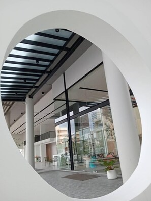 Un edificio moderno con fachada de vidrio, amplias columnas y estructura de techo metálico.