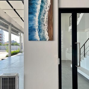 An interior corridor with a large painting of ocean waves on the wall, a modern staircase, and a glass door leading to another area. - Hatyai Midtown Hotel (Hat Yai)