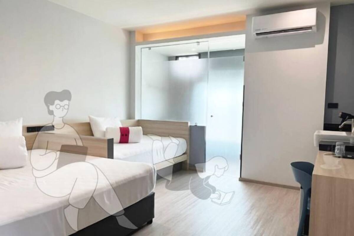 Une chambre d’hôtel moderne équipée de deux lits, d’un bureau et d’un espace douche.