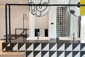 A bathroom with a black and white geometric tile backsplash, a large mirror, and a modern sink.