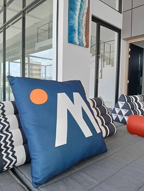 A modern interior with a seating area featuring a large blue pillow with a white letter 'M' and a smaller orange circle. - Hatyai Midtown Hotel (Hat Yai)