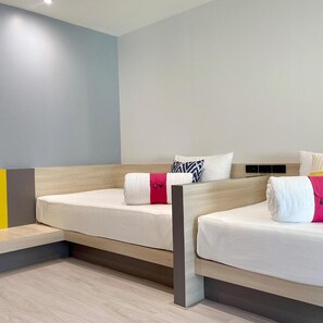 Una habitación de hotel moderna con dos camas individuales, cabecero de madera y suelo de color claro.