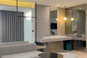 Une salle de bain moderne avec un canapé, deux lavabos et un grand miroir.