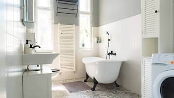 A modern bathroom with a freestanding bathtub, a built-in sink, and a front-loading washing machine.