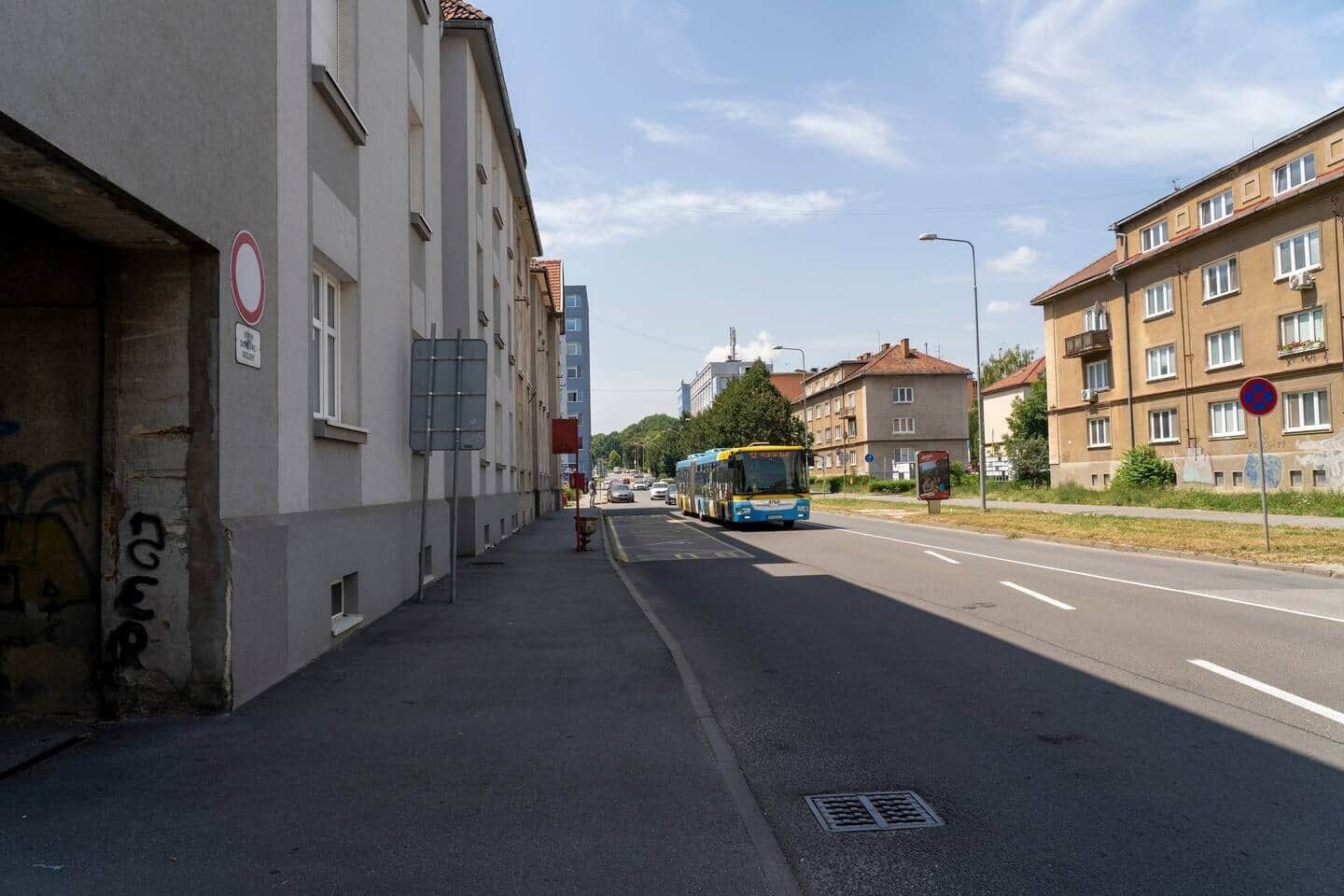A street with buildings, a bus, and a sidewalk.