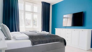 Une chambre à coucher moderne avec un lit, un téléviseur et une fenêtre avec des rideaux.