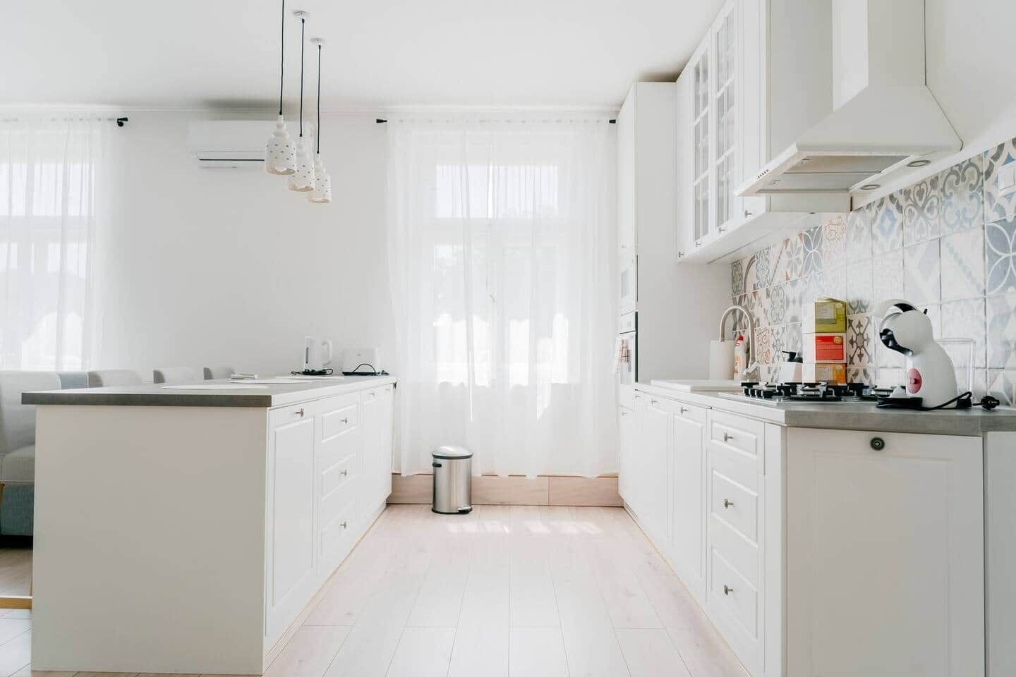 Une cuisine moderne avec des meubles blancs, un îlot central et une cuisinière à gaz.