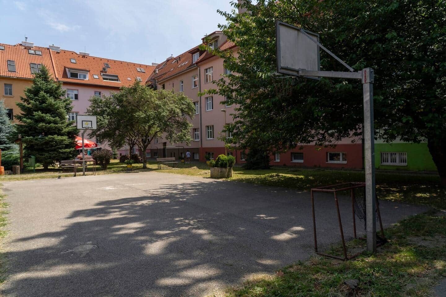 A courtyard with a basketball court, benches, and trees.