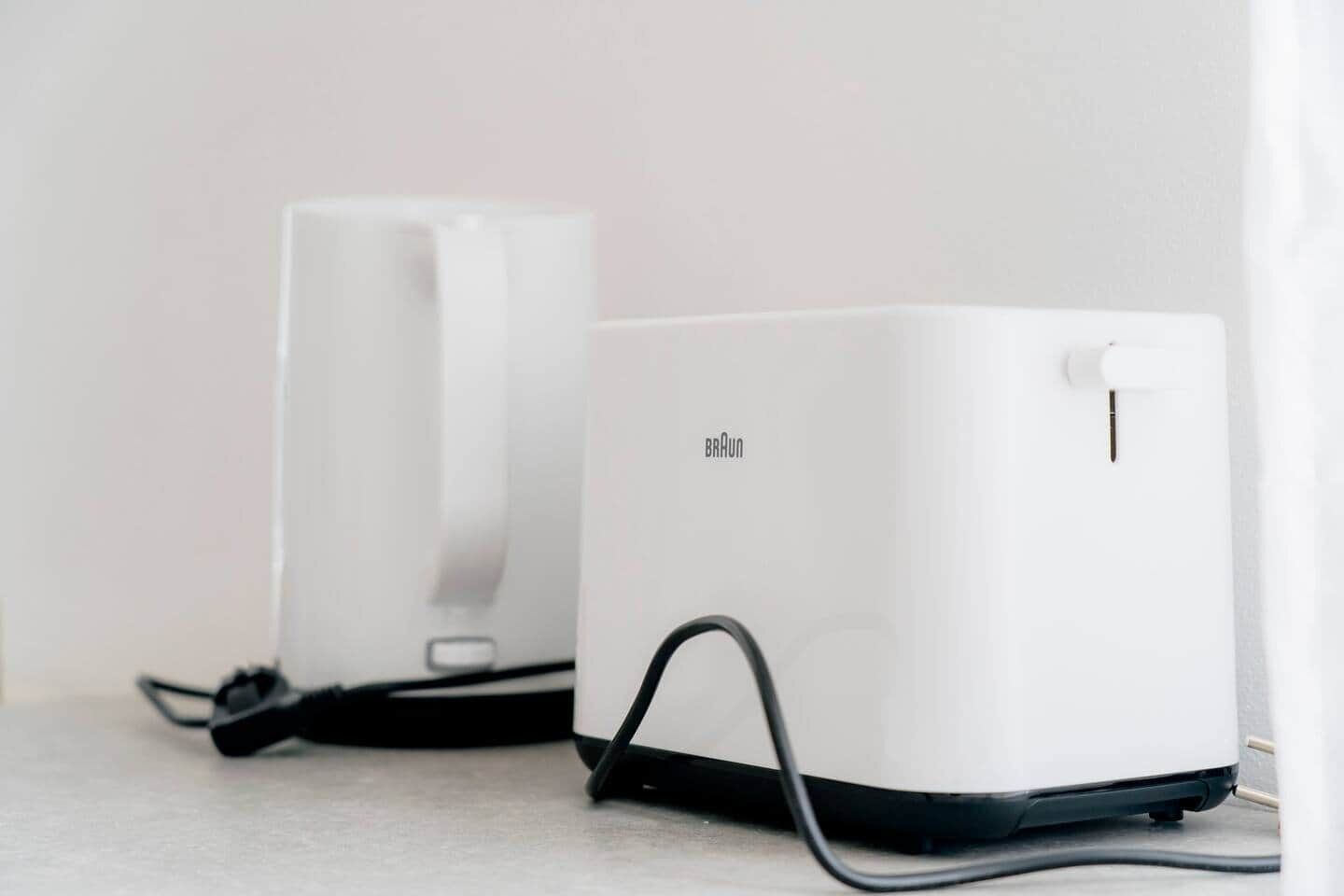 Two white Braun hairdryers on a light-colored surface.