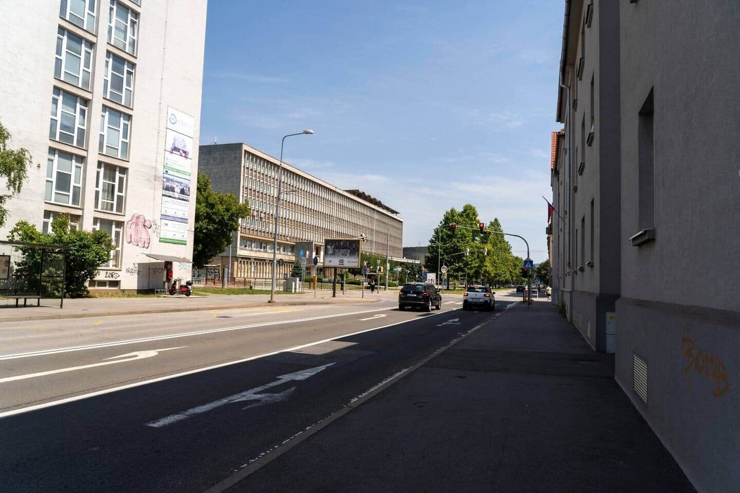 Straatbeeld met gebouwen, een bushalte en auto's.