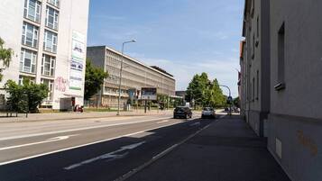Straatbeeld met gebouwen, een bushalte en auto's.
