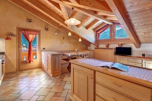 A kitchen with wooden cabinets, a dining table, and a window with a view of mountains.