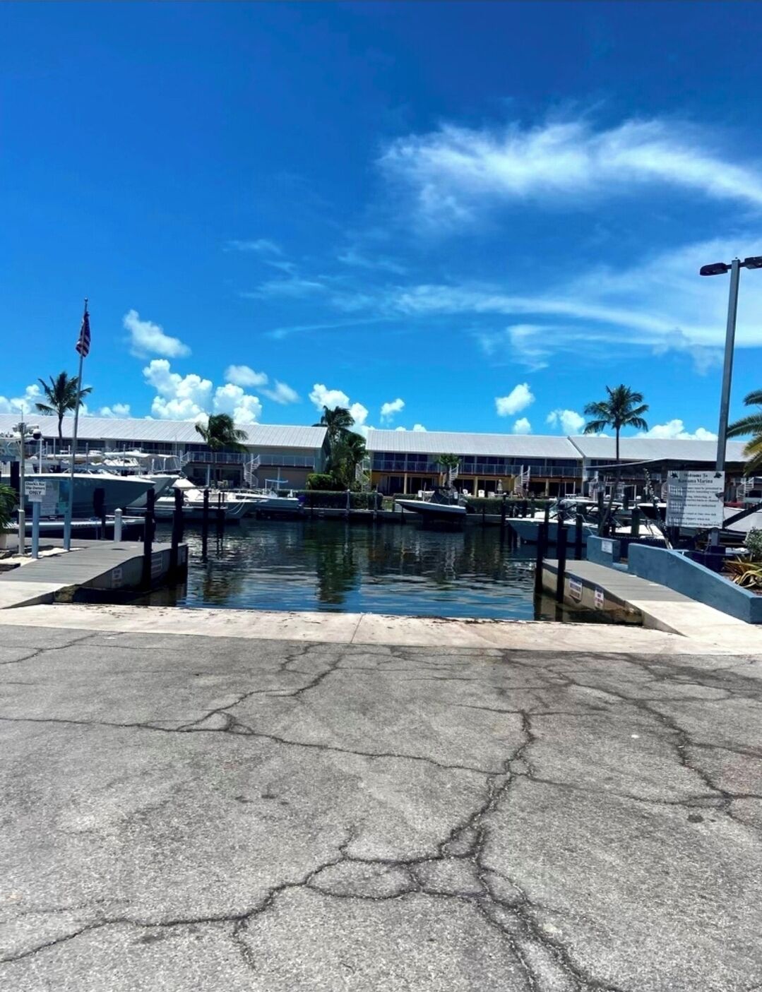 A marina with boats docked, a clear blue sky, and a building with a sign in the background.