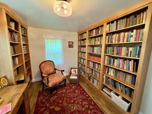 Ein Zimmer mit einem Holzbett, einem roten Teppich mit Muster und Bücherregalen voller Bücher.