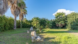 Un jardín con palmeras, cielo despejado y césped cuidado.