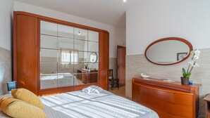 Un dormitorio con una cama grande, un armario de madera, un tocador y un espejo.