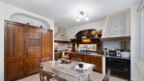 Una cocina con armarios de madera, una mesa de comedor con sillas, un microondas y un lavamanos.