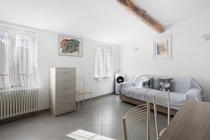 A modern bedroom with a bed, a dresser, a chair, and a radiator.