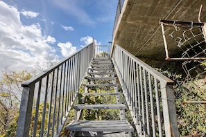 A metal staircase leading up to a building with a concrete wall and a metal fence.