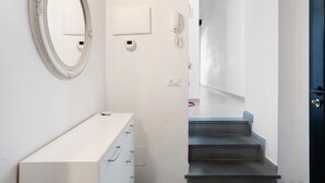 A hallway with a white dresser, a mirror, a wall-mounted phone, and a door leading to a staircase. - Apartment 'Donadelmar2' with Sea View and Wi-Fi (Riomaggiore)