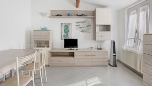 A modern kitchen with a wooden dining table, chairs, a built-in TV, and a white cabinet. - Apartment 'Donadelmar2' with Sea View and Wi-Fi (Riomaggiore)
