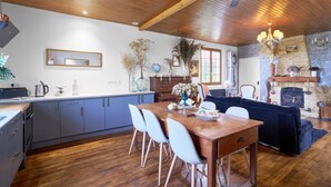 Una cocina moderna con armarios de madera, una mesa de comedor con sillas y una sala de estar con sofá y chimenea.