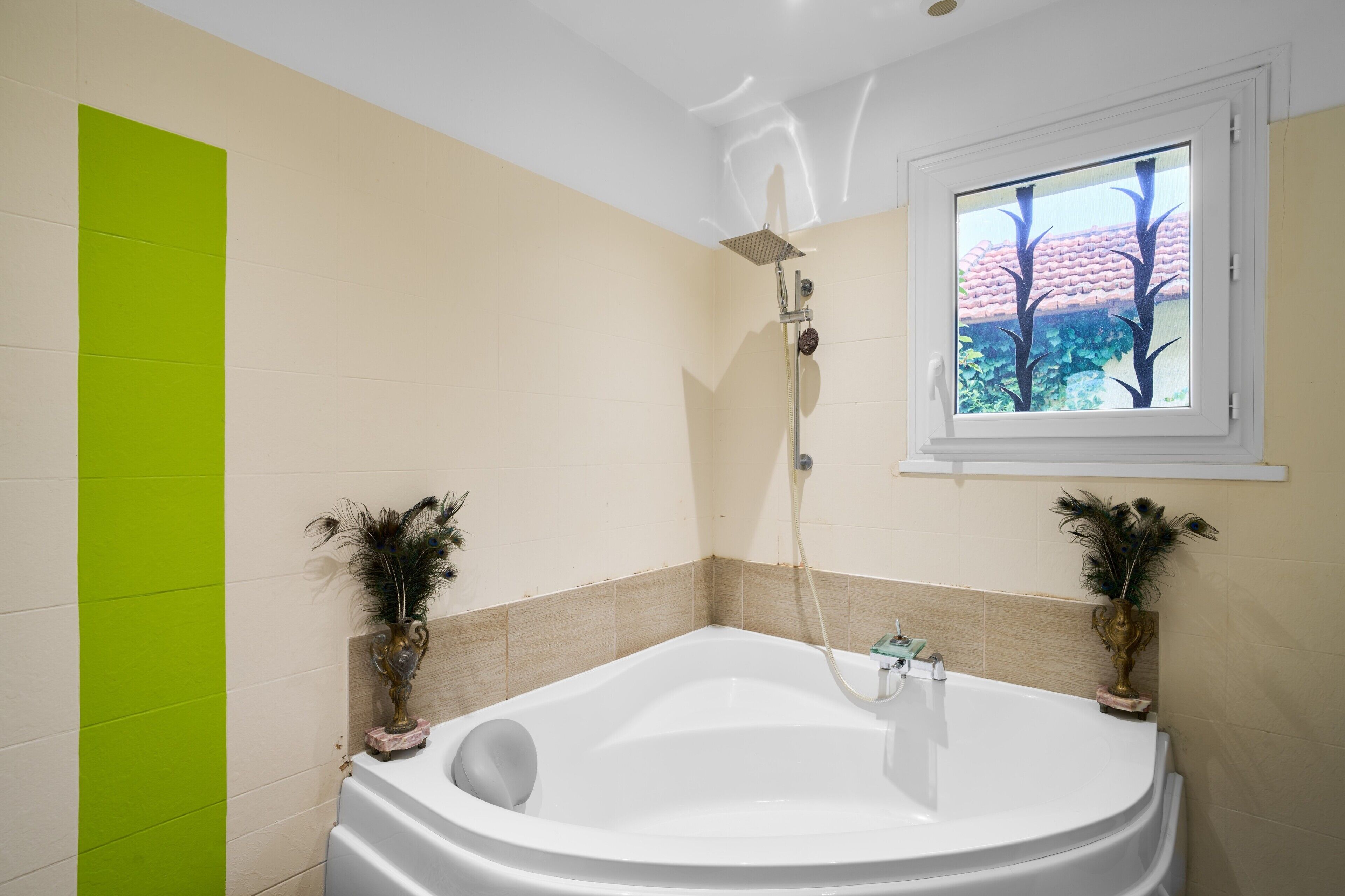 Ein Badezimmer mit einer Badewanne, einem Fenster mit Ausblick und zwei dekorativen Vasen.
