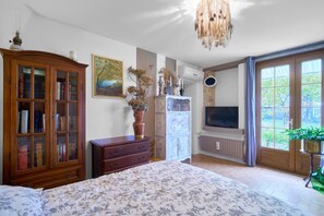 A bedroom with a bed, a wooden cabinet, a dresser, a television, and a window with curtains. - Gite de La Fontaine de Laumede (Saint-Chamassy)
