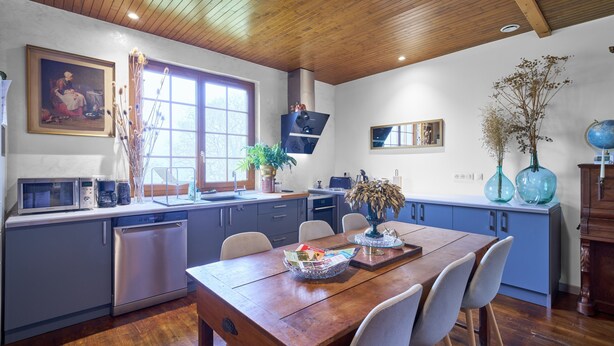 Una cocina moderna con techo de madera, un comedor con mesa de madera y un ventanal grande.