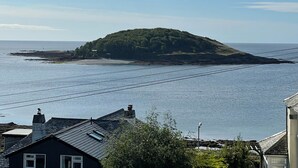 A coastal view with a small island, houses, and a clear sky.