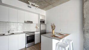 Eine moderne Küche mit weißen Schränken, Edelstahlgeräten und einer zentralen Kochinsel mit Sitzgelegenheiten.
