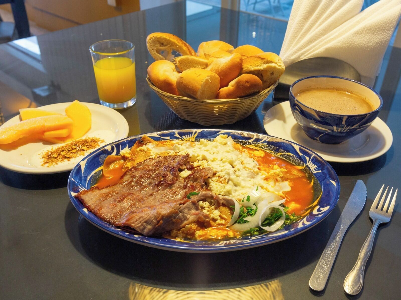 Eine Mahlzeit mit Fleisch, Gemüse und einer Schüssel Suppe auf einem Tisch.