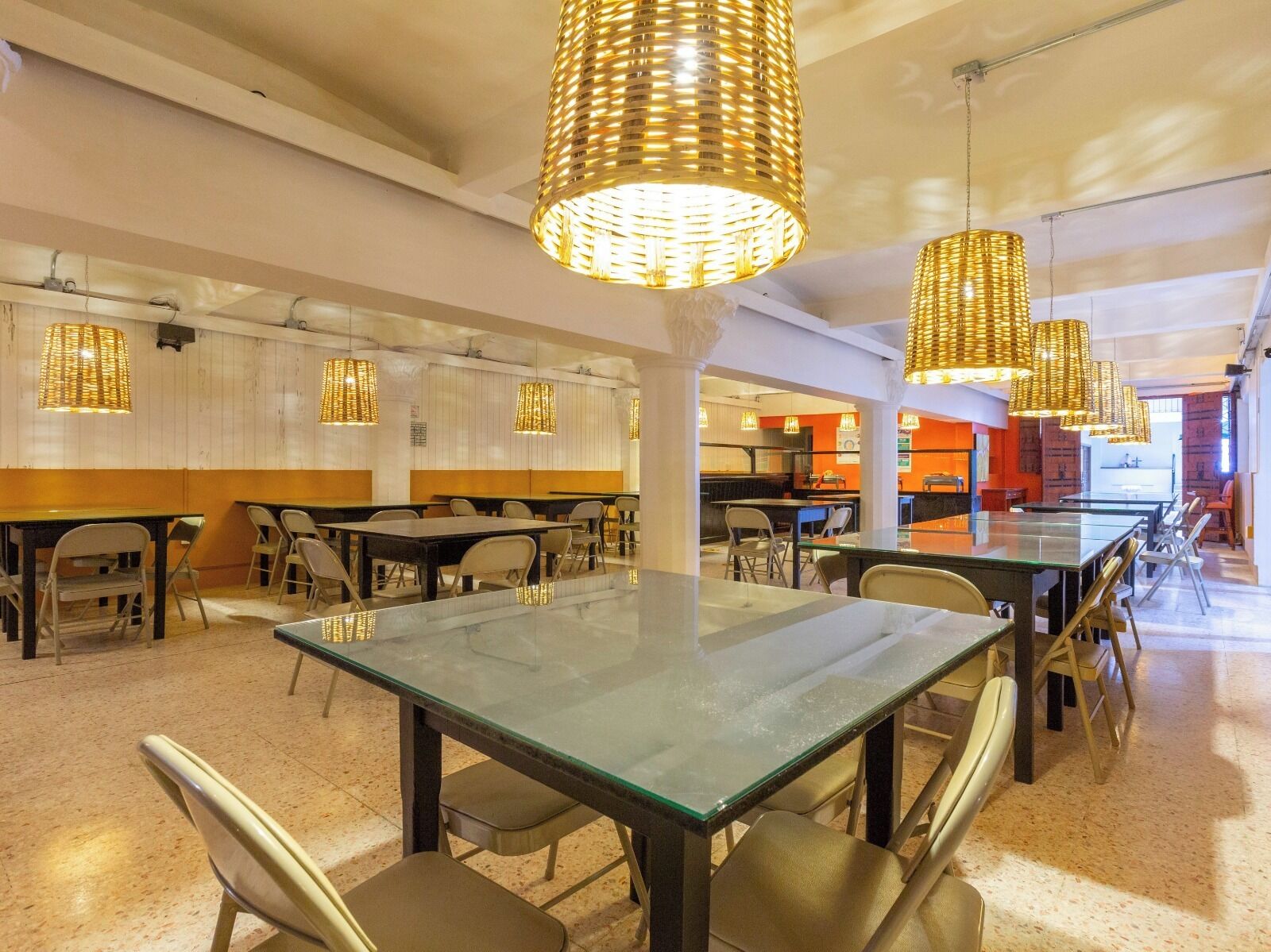 Un restaurante moderno con mesas y sillas de vidrio, iluminación cálida y un diseño limpio y abierto.