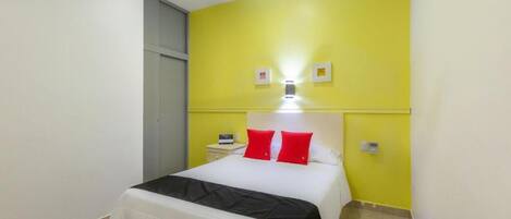A hotel room with a bed, a nightstand, a lamp, and a ceiling fan.
