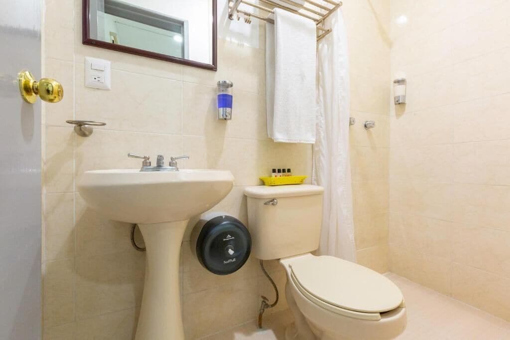 Un bagno con lavabo a piedistallo, water e portasciugamani.