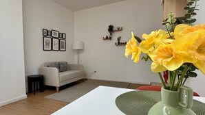 Una sala de estar con sofá, mesa de centro, un florero y adornos en la pared.