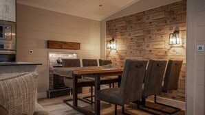 Un coin repas avec une table et des chaises en bois, un four encastré et un mur décoré d’un motif en briques, agrémenté d’appliques murales.