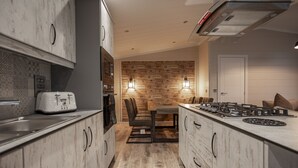 Une cuisine moderne avec des meubles en bois, une cuisinière encastrée et un coin repas comprenant une table et des chaises en bois.